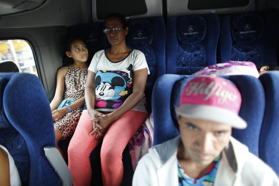 In this Sept. 4, 2018 photo, 10-year-old Venezuelan Angelis looks up at her mother Sandra Cadiz on the back of a bus at the stop in San Juan de la Paz, Colombia, on their journey to Peru. It was in San Juan De La Paz that Cadiz decided to switch her strategy: She'd barter with the 250,000 or so pesos - about $80 - she'd now collected from generous Colombians who'd spotted her walking and given her money to buy her way on to buses. (AP Photo/Ariana Cubillos)