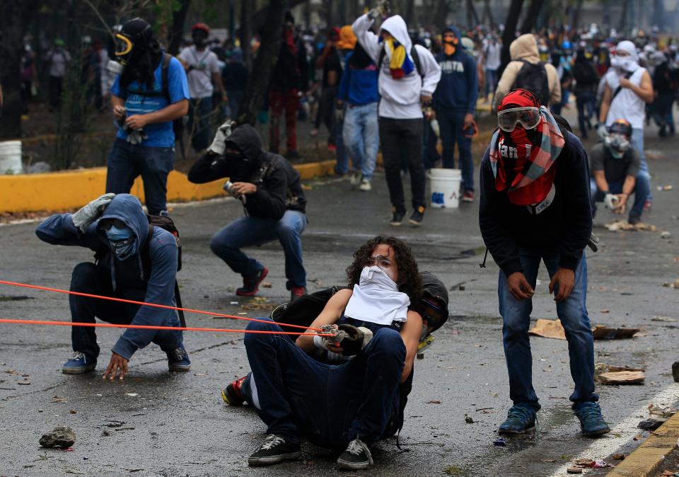 Manifestantes lanzan piedras contra una la Policía Nacional Bolivariana durante enfrentamientos fuera de la Universidad Central de Venezuela (UCV), en el marco de protestas contra el gobierno en Caracas, Venezuela, el jueves 3 de abril de 2014. (Foto AP/Fernando Llano)