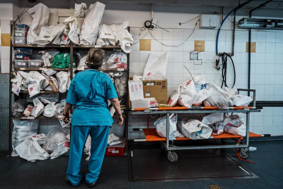 A woman stands before shelves of white bags