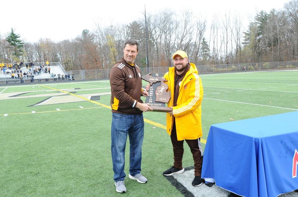 Brian Hassler hands off the 2022 MHSAA Champion Trophy to Division I Boys Soccer at Rochester Adams High School.