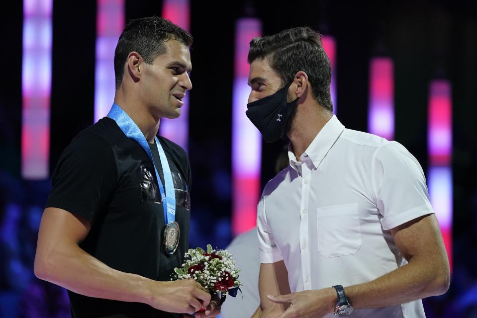 Michael Andrew talks to Michael Phelps at the medal ceremony for the men's 200 individual medley during wave 2 of the U.S. Olympic Swim Trials on Friday, June 18, 2021, in Omaha, Neb. (AP Photo/Charlie Neibergall)