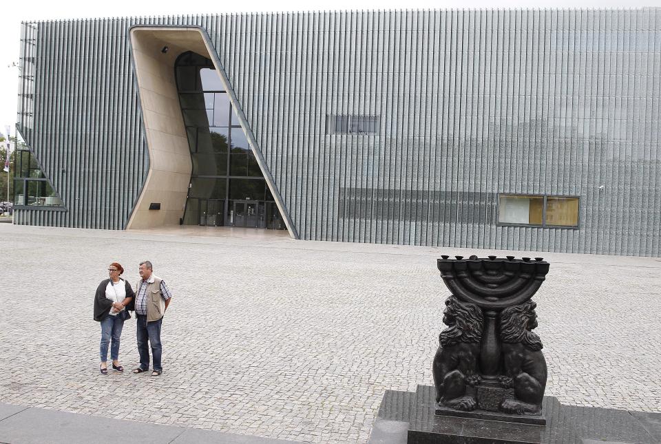 People stand in front of the Museum of the History of Polish Jews 'POLIN' in Warsaw, Poland, Tuesday, 16 July 2019. A Jewish association has said that some private donors to Poland's renowned Jewish history museum have suspended their donations out of concern over the government's failure to extend the term of its director. (AP Photo/Czarek Sokolowski)