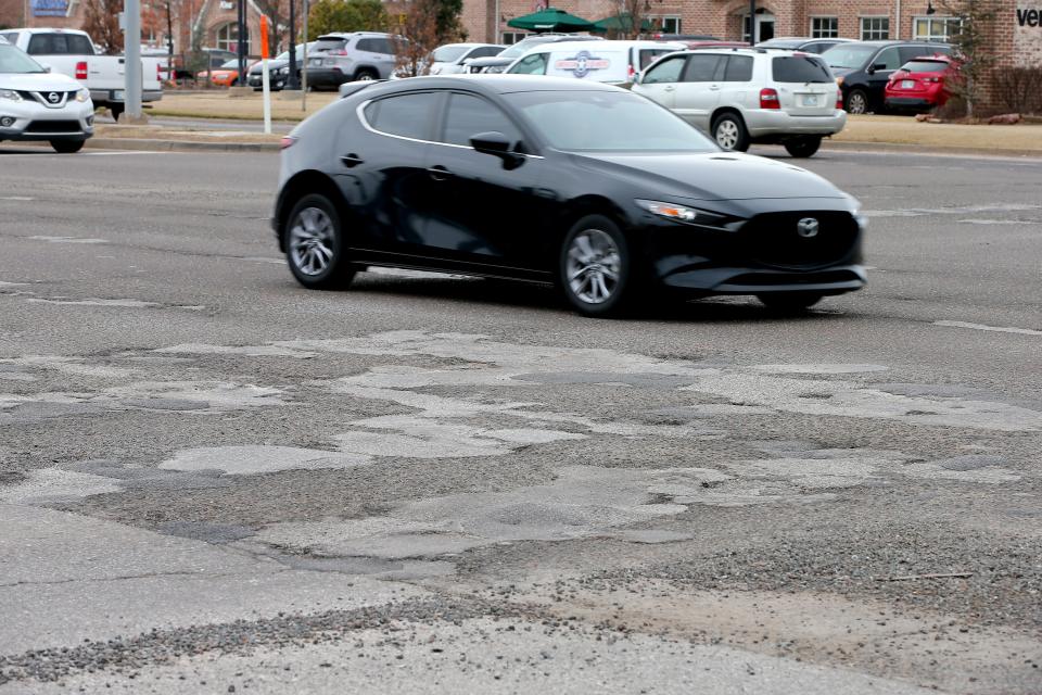 A car drives over patches and potholes March 13 at the intersection of S Broadway and 15th Street in Edmond.