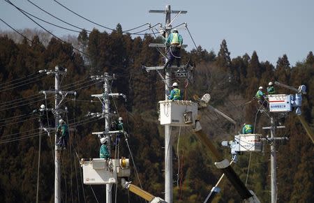 Workers climb poles to fix power lines in Minamisanriku, Miyagi prefecture, after the area was devastated by the March 11 magnitude 9.0 earthquake and tsunami, in this April 6, 2011 file photo. REUTERS/Toru Hanai/Files