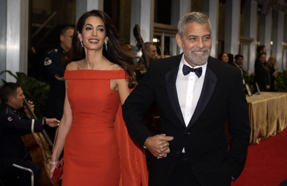 Ce 4 décembre, George et Amal Clooney ont de nouveau rayonné sur tapis rouge. Et pas n’importe lequel. Le couple a assisté aux Kennedy Center Honors, à Washington D.C, au cœur du Parc du Président de la Maison Blanche. Cette cérémonie annuelle récompense les artistes américains aux carrières ayant contribué à l’essor de la culture américaine. Sans surprise, George Clooney était l’un des prestigieux lauréats de cette soirée. Acteur phare de sa génération, George Clooney n’est plus à présenter. C’est pourquoi la star de la saga « Ocean’s » a été récompensé pour l’ensemble de son œuvre. Pour recevoir cet honneur, il était accompagné par son épouse, l’avocate Amal Clooney. Marié depuis 2014, ce couple doré d’Hollywood continue de créer l’engouement à chaque apparition en public. Lire aussi >> Couple de légende : George et Amal Clooney, la dolce vita à HollywoodGeorge et Amal Clooney, toujours complices Sur le tapis rouge, Amal Clooney portait une longue robe rouge signée Valentino. Avec ce look on ne peut plus glamour, l’avocate anglo-libanaise rayonnait aux côtés de son époux. L’acteur a même été surpris en train d’arranger la robe de sa compagne, s’assurant qu’elle apparaîtrait sous son plus beau jour devant les caméras. Le couple a également été aperçu avec Nick et Nina Clooney, les parents de George Clooney. La famille était réunie au complet pour recevoir le trophée de l’acteur oscarisé. « Grandissant dans une petite ville du Kentucky, je n’aurais jamais pu imaginer qu’un jour je serais aux Kennedy Center Honors », a déclaré George Clooney, comme rapporté par « ABC News », « Être mentionné auprès de tous ces incroyables artistes est un honneur. C’est une énorme surprise pour toute la famille Clooney. »Parmi les autres lauréats et invités, d’autres noms de l’industrie. Le groupe U2, Amy Grant et Ariana DeBose, la star de « West Side Story », ont répondu présents. La soirée était placée sous la supervision de Joe Biden qui a reçu tous les artistes au cœur de la Maison Blanche. Le président des États-Unis était accompagné par son épouse, Jill Biden, et a donné un discours en l’honneur des lauréats.