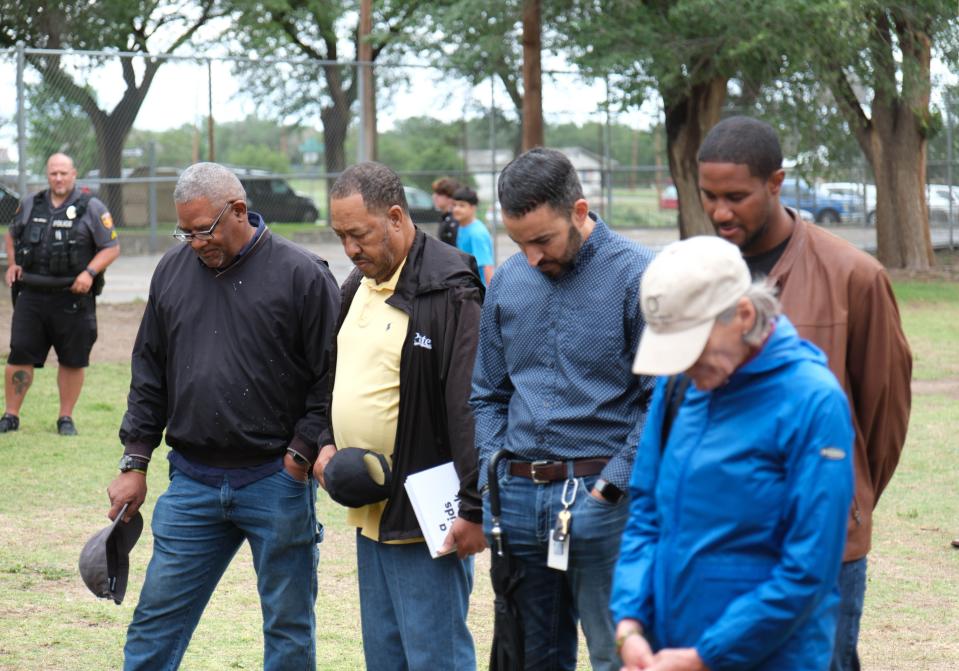 Members of the community bow their head in prayer Wednesday at the marker ceremony for Bones Hooks at Bones Hooks Park.