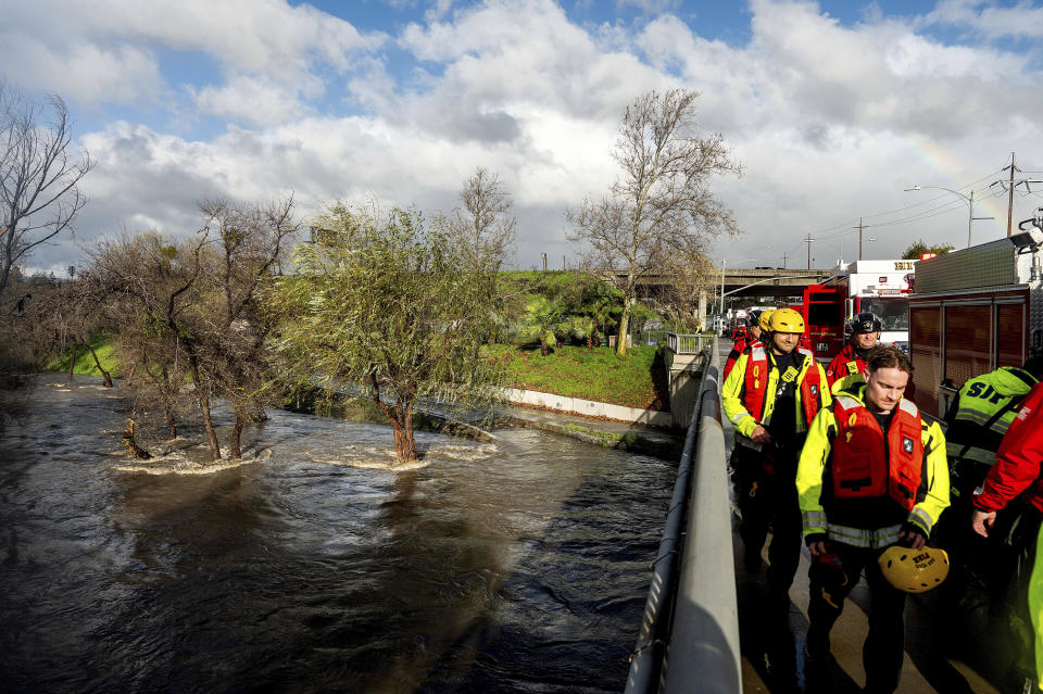 Search and rescue workers return to their vehicles after rescuing homeless encampment residents surrounded by Guadalupe River floodwaters on Sunday, Feb. 4, 2024, in San Jose, Calif. High winds and heavy rainfall are impacting the region. (AP Photo/Noah Berger)