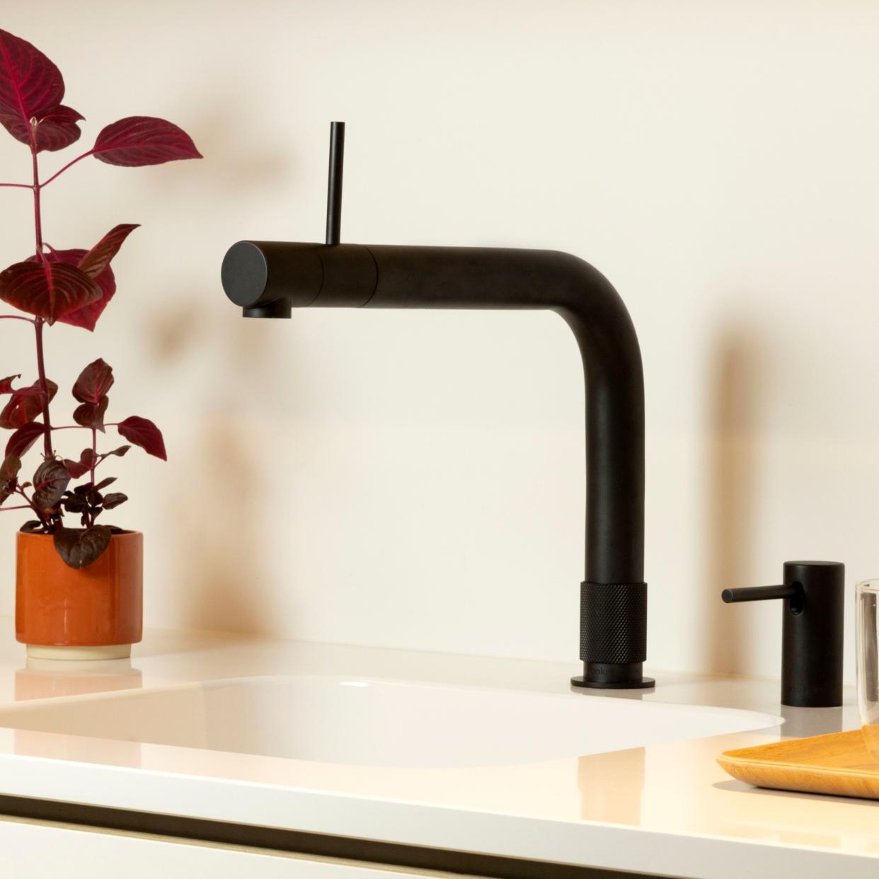  Matte black boiling water tap on white sink next to red plant. 