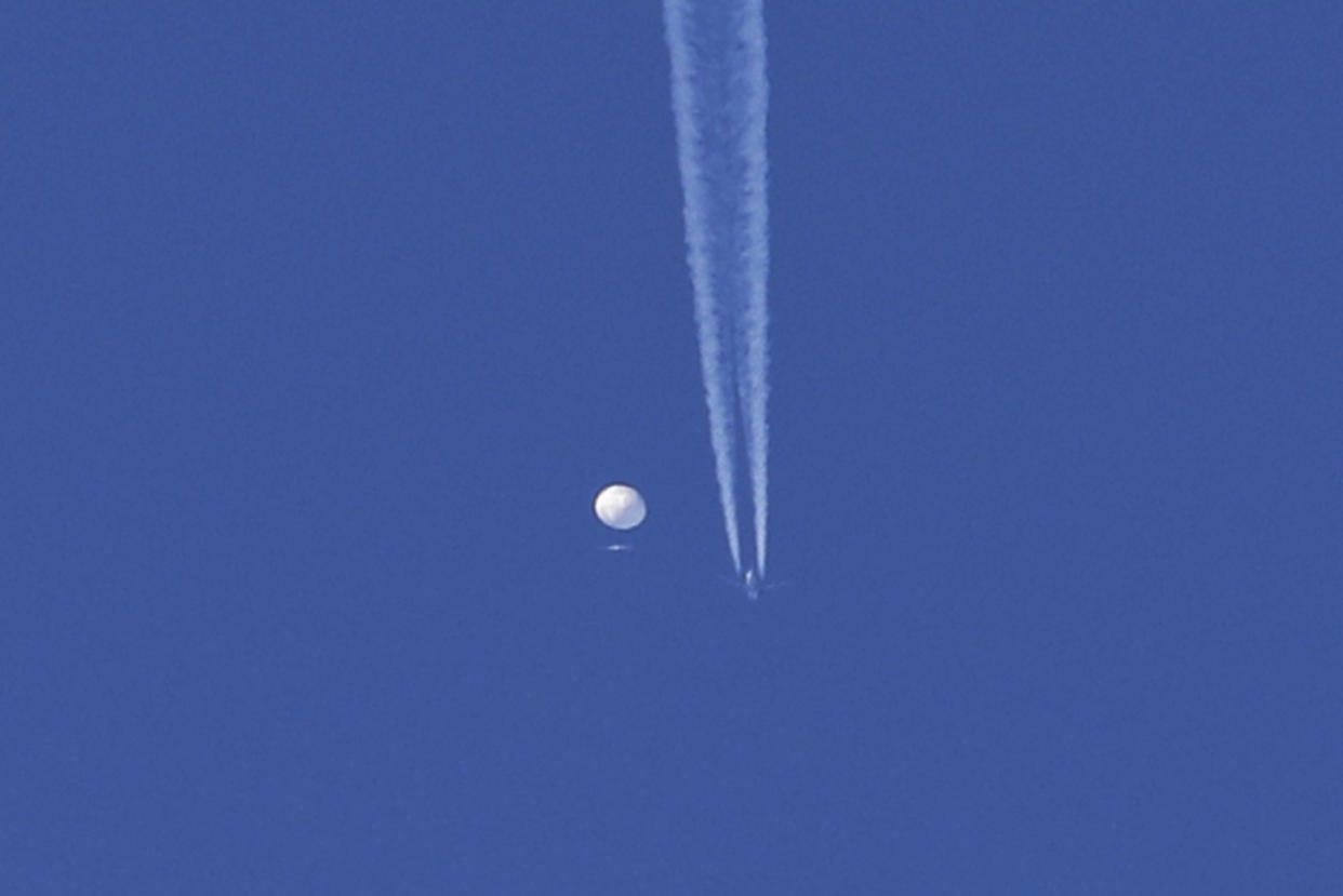 An airplane flies below a large balloon as it drifts above the Kingstown, N.C. (Brian Branch via AP)