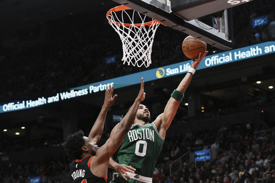 Boston Celtics forward Jayson Tatum (0) goes for the layup as Toronto Raptors forward Thaddeus Young (21) defends during the second half of an NBA basketball game in Toronto, Monday, Dec. 5, 2022. (Chris Young/The Canadian Press via AP)