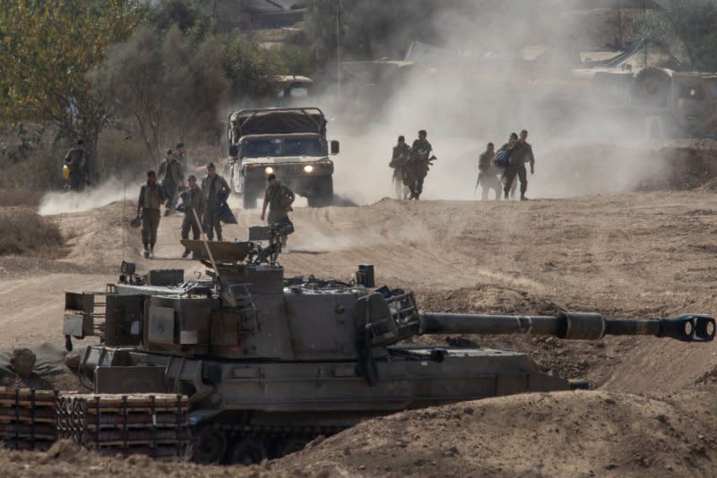 Israeli soldiers walk toward a 155mm self-propelled Howitzer in a staging position in southern Israel near the border with the Gaza Strip on Tuesday. Israeli forces continue to fight inside the Gaza Strip with airstrikes and artillery. Photo by Jim Hollander/UPI