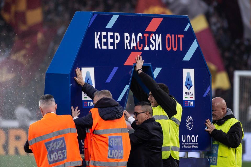 Field staff place a board with the Serie A crest and the slogan of the anti-racism campaign before a match on March 19, 2023, in Rome. (Ivan Romano/Getty Images)
