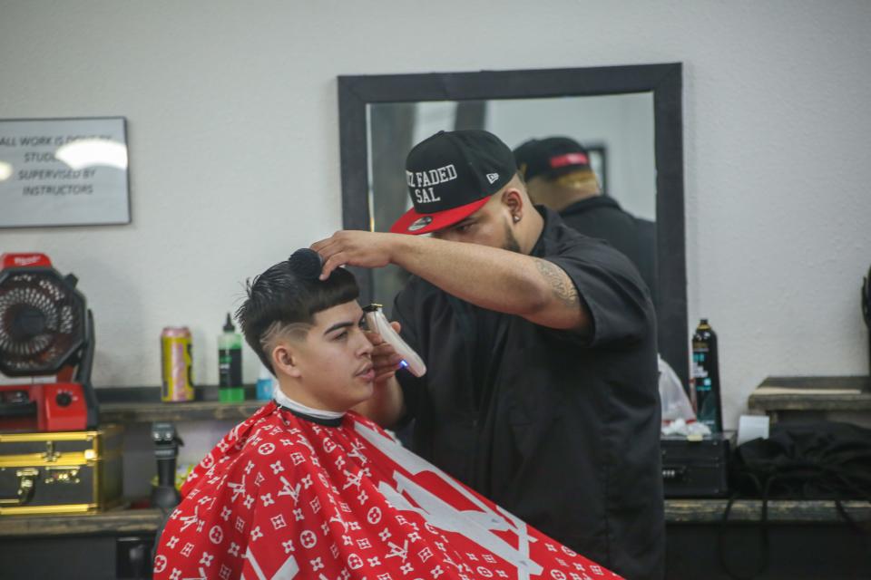 A student cuts a client's hair at East to West Academy in Visalia.