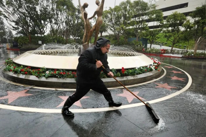 Los Angeles, California-Jan. 4, 2023-Mathew Prado, who works at the Sheraton Hotel at Universal Studio, sweeps water from the front drive. Heavy rain is falling in Los Angeles as another winter storm moves in. (Carolyn Cole / Los Angeles Times)