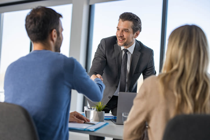 A financial advisor meeting with two life insurance leads.