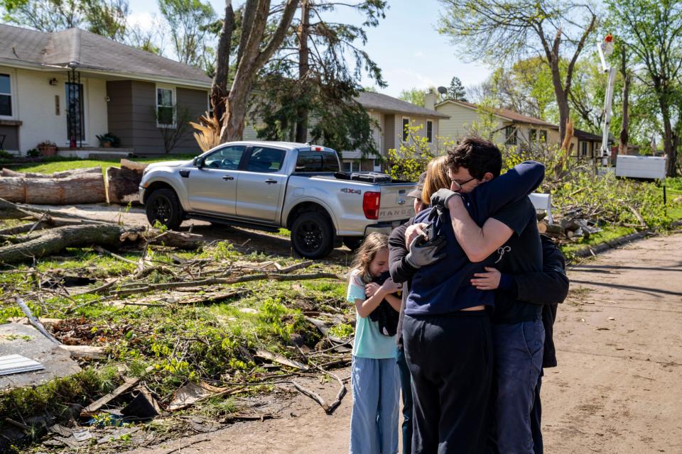 Neighbors embrace Penny Thomsen outside of her home in Pleasant Hill, Iowa, on Saturday, April 27, 2024. The Des Moines suburb was one of multiple cities hit as tornados ripped across the state Friday evening. (The Des Moines Register via AP)