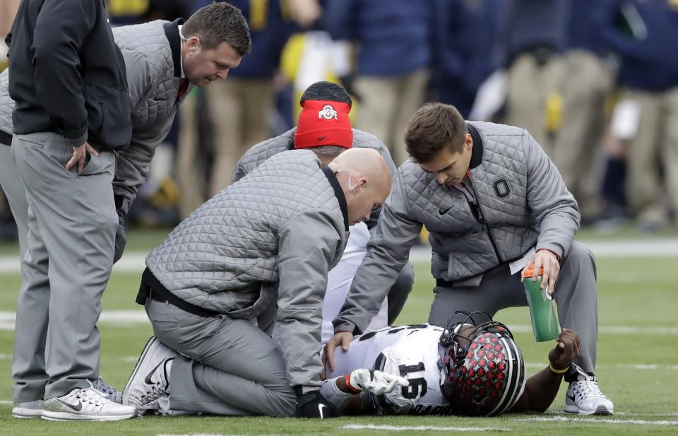 Ohio State quarterback J.T. Barrett (16) is looked at by team officials after being sacked during the second half of an NCAA college football game, Saturday, Nov. 25, 2017, in Ann Arbor, Mich. Barrett did not return after the sack. (AP Photo/Carlos Osorio)