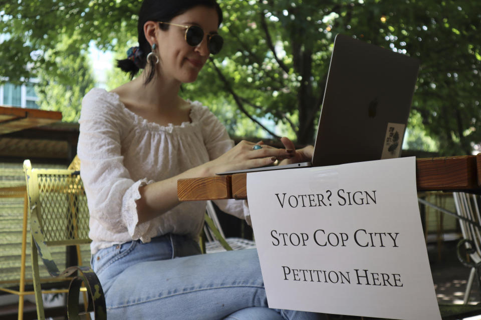 Activist Hannah Riley works on her laptop at Muchacho, a local taco restaurant, while gathering signatures from fellow voters, in Atlanta, Thursday, July 13, 2023. Organizers are trying to force a referendum that would allow voters to decide the fate of a proposed police and training center, but attorneys for the city say the petition drive is invalid. (AP Photo/R.J. Rico)