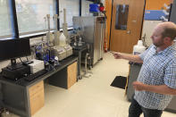 Geologist Fred McLaughlin points to lab equipment Aug. 10, 2022, at the University of Wyoming School of Energy Resources in Laramie, Wyo. Researchers use the equipment to study samples from deep rock formations that have potential for storing carbon dioxide underground. New federal tax credits and billions of dollars in new funding are likely to boost such efforts to counter climate change. (AP Photo/Mead Gruver)