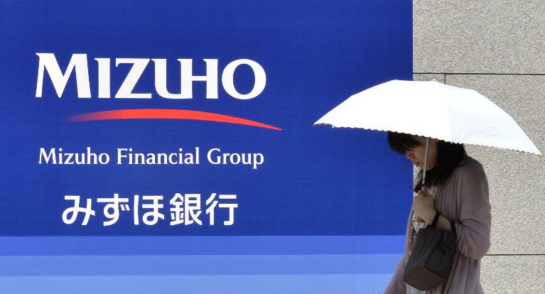 A woman walks in front of a signboard for Japan's Mizuho Financial Group in Tokyo on May 15, 2013