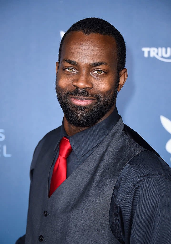 Damion Poitier  smiles in a suit vest, dress shirt, and tie at event