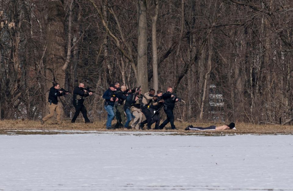 Police approach a person of interest on the south bank of the North River in Bridgewater, Va. following a shooting at Bridgewater College Tuesday.