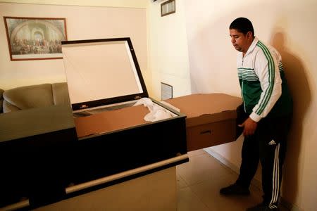 A man puts a cardboard coffin inside a crate at a mortuary in Valencia, in the state of Carabobo, Venezuela August 25, 2016. Picture taken August 25, 2016. REUTERS/Marco Bello