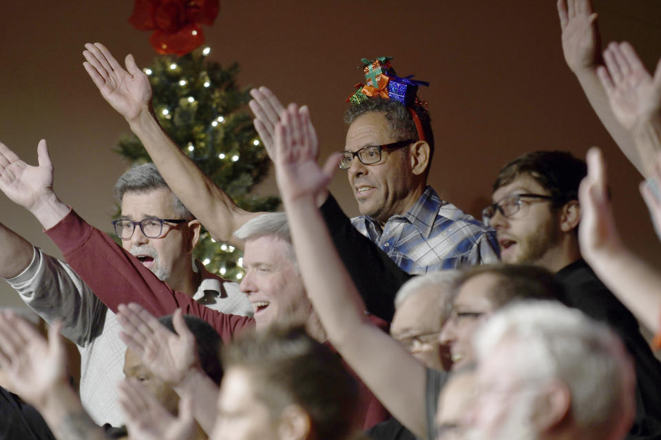 Rod Gilmore, center, sings during a Christmas show rehearsal in Colorado Springs, Colo., on Wednesday, Nov. 30, 2022. The Out Loud Colorado Springs Men's Chorus has taken an active role in the healing process after a Nov. 19 attack killed five people at an LGBTQ nightclub in Colorado Springs. Gilmore, who was at the club the night of the shooting, said he nearly re-entered the closet he'd lived in for 55 years but decided not to because of support from his fellow chorus members. (AP Photo/Thomas Peipert)