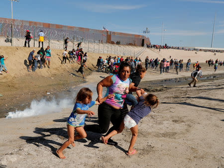 FILE PHOTO: A migrant family, part of a caravan of thousands traveling from Central America en route to the United States, run away from tear gas in front of the border wall between the U.S and Mexico in Tijuana, Mexico November 25, 2018. Reuters photographer Kim Kyung-Hoon: REUTERS/Kim Kyung-Hoon/File Photo