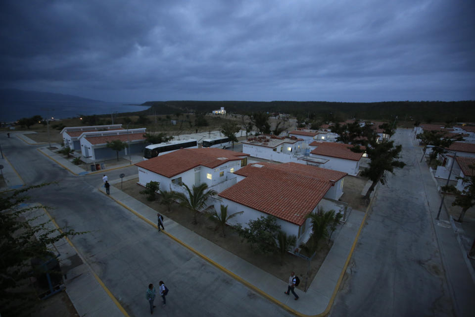 Journalists walk through streets of bungalows that once served as prison dormitories at the Morelos detention center during a media tour of the now closed Islas Marias penal colony located off Mexico's Pacific coast, at dawn Saturday, March 16, 2019. The penal colony was done in by high costs, almost $150 per day per inmate, far beyond what mainland prison costs, and by the increasing space available at mainland prisons as legal reforms reduced jail populations. (AP Photo/Rebecca Blackwell)