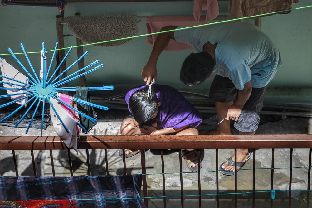 A man is pictured trimming his friend’s hair at their home during the movement control order in Kota Damansara April 12, 2020. — Picture by Ahmad Zamzahuri