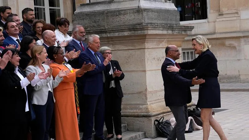 French far-right leader Marine Le Pen, right, arrives to pose with newly elected Parliament members of the National Rally party at the National Assembly, Wednesday, July 10, 2024, in Paris. French voters have given a broad leftist coalition the most parliamentary seats in a pivotal legislative election that has kept the far right from power but has put France in the unprecedented position of having no dominant political bloc in Parliament.