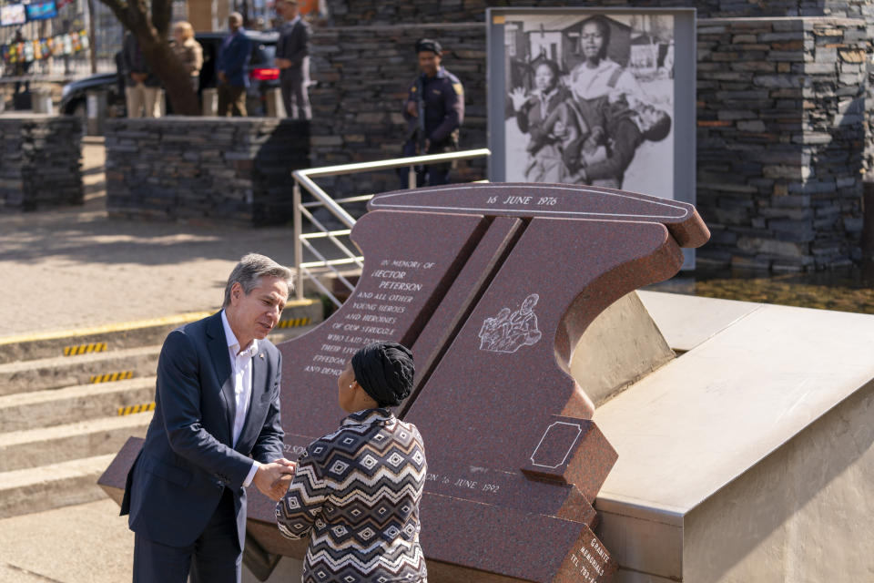 Secretary of State Antony Blinken greets Antoinette Sithole, the sister of the late Hector Pieterson, as he visits the Hector Pieterson Memorial in Soweto, South Africa, Sunday, Aug. 7, 2022. Peaceful child protesters were gunned down by police 30 years ago in an attack that awakened the world to the brutality of the apartheid regime. At top right, is an iconic picture of Antoinette, running with mouth open in a scream alongside a friend carrying the body of her slain brother, Hector. (AP Photo/Andrew Harnik, Pool)