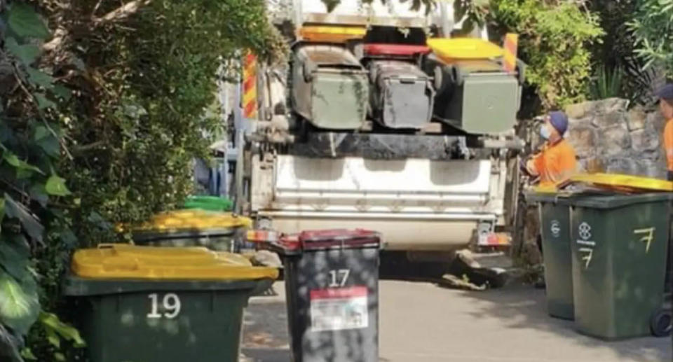 A garbage truck picking up red and yellow bins