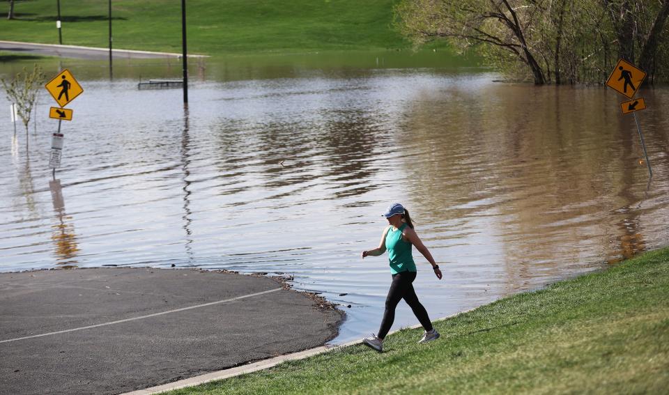 A walker goes around the flooded road where a pond has formed in Sugarhouse Park in Salt Lake City on Tuesday, May 2, 2023. | Jeffrey D. Allred, Deseret News