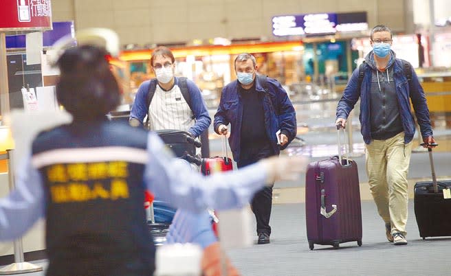 北桃接連2起防疫旅館群聚，指揮中心已規畫對全台防疫旅館進行總體檢。圖為在桃機第二航廈入境大廳內，防疫人員引導剛入境的旅客準備採檢。圖中人非新聞當事人。（范揚光攝）