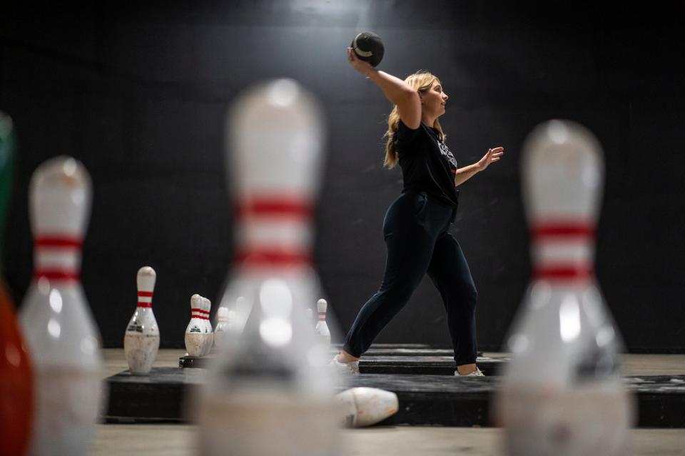 Fowling Warehouse front desk worker Carsyn Bruns throws a football while playing against a co-worker while waiting for customers shortly after opening on Friday, Nov. 3, 2023, at the business in Ypsilanti.