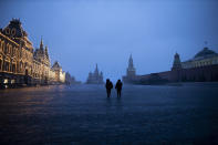 Two police officers patrol an almost empty Red Square, with St. Basil's Cathedral, center, and Spasskaya Tower and the Kremlin Wall, right, at the time when its usually very crowded in Moscow, Russia, March 30, 2020. (AP Photo/Alexander Zemlianichenko)