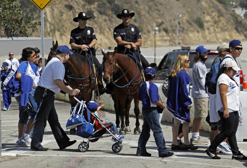 FILE - This April 10, 2012 file photo shows Los Angeles Police mounted patrol officers Steve Cooper, left, aboard Jimbo and Roger Johnson on Ranger watching Dodger fans arrive for the home opener baseball game at Dodger Stadium in Los Angeles. A driver was beaten in the Dodger Stadium parking lot after a weekend game and four people were arrested on suspicion of assault with a deadly weapon, police said Monday, May 21, 2012. (AP Photo/Reed Saxon, File)