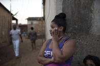 A woman stands against a wall during the distribution of donated food, kits of cleaning products, and protective face masks amid the new coronavirus pandemic, at the Maria Joaquina "Quilombo" in Cabo Frio, on the outskirts of Rio de Janeiro, Brazil, Sunday, July 12, 2020. Often disconnected from urban life even when within city limits, "Quilombos" have a relatively high incidence of poverty and can be confused with poor neighborhoods. (AP Photo/Silvia Izquierdo)