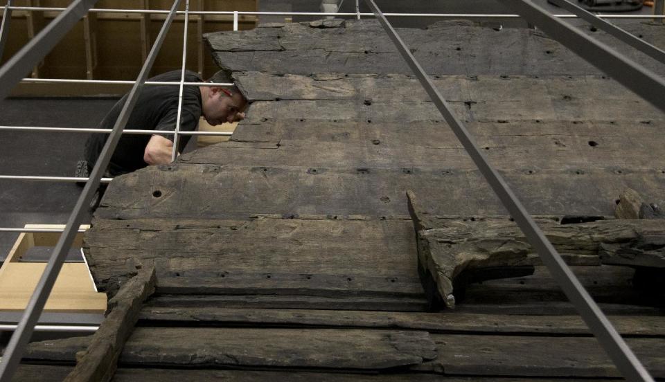 A conservator helps with the final assembly of The Viking ship known as Roskilde 6, of which about 20 per cent of the timber remains and which is dated to around 1025 AD, at the British Museum in London, Friday, Jan. 17, 2014. The ship was excavated from the banks of Roskilde Fjord, Denmark in 1997. It will be part of a Viking exhibition at the museum that will open to the public on March. 6, 2014. (AP Photo/Alastair Grant)