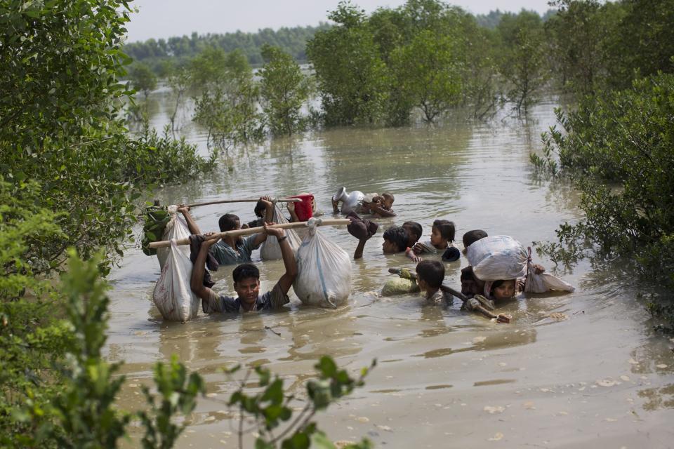 -FILE- In this Tuesday, Sept. 5, 2017, file photo a Rohingya family reaches the Bangladesh border after crossing a creek of the Naf river on the border with Myanmmar, in Cox's Bazar's Teknaf area. Gambia has filed a case at the United Nations' highest court in The Hague, Netherlands, Monday, Nov. 11, 2019, accusing Myanmar of genocide in its campaign against the Rohingya Muslim minority. A statement released Monday by lawyers for Gambia says the case also asks the International Court of Justice to order measures "to stop Myanmar's genocidal conduct immediately." (AP Photo/Bernat Armangue, file)