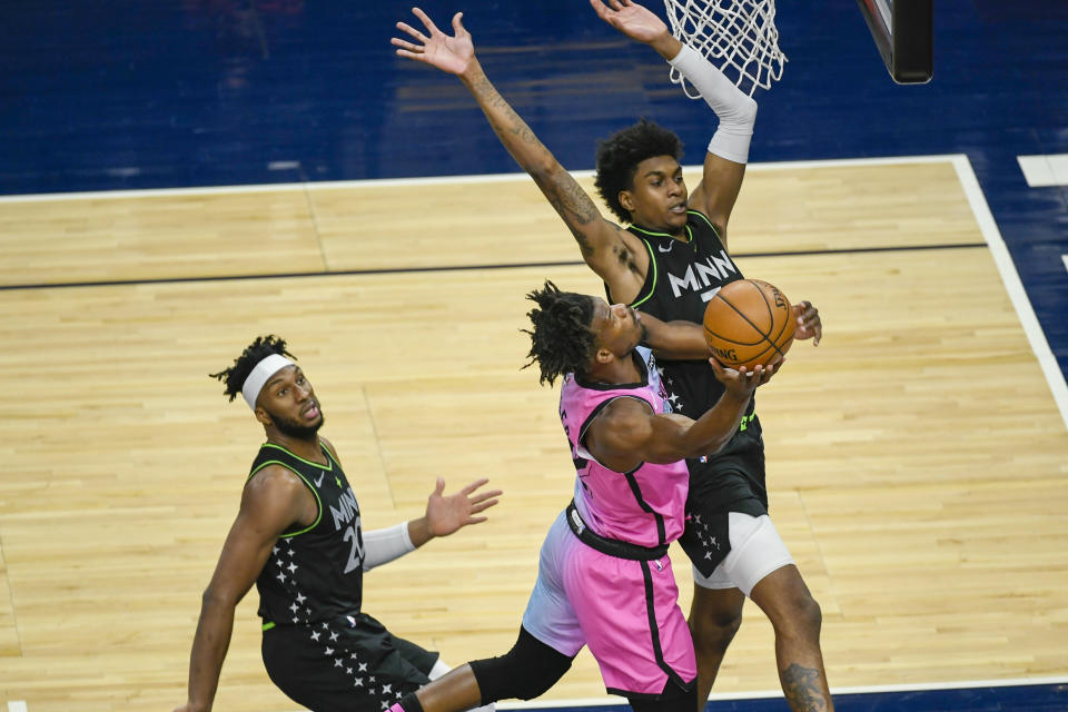 Miami Heat forward Jimmy Butler, center, goes up for a shot past Minnesota Timberwolves forward Jaden McDaniels, right, and forward Josh Okogie during the first half of an NBA basketball game Friday, April 16, 2021, in Minneapolis. (AP Photo/Craig Lassig)