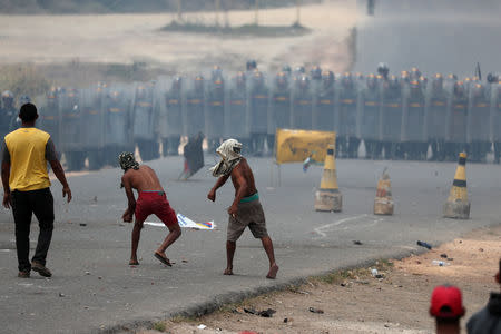 People throw stones at Venezuelan national guard members, at the border, seen from in Pacaraima, Brazil February 24, 2019. REUTERS/Ricardo Moraes