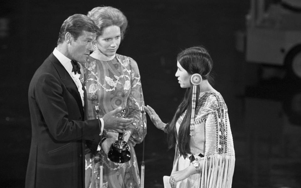 Sacheen Littlefeather refuses to take the Oscar from Roger Moore as Liv Ullman watches on - Bettmann