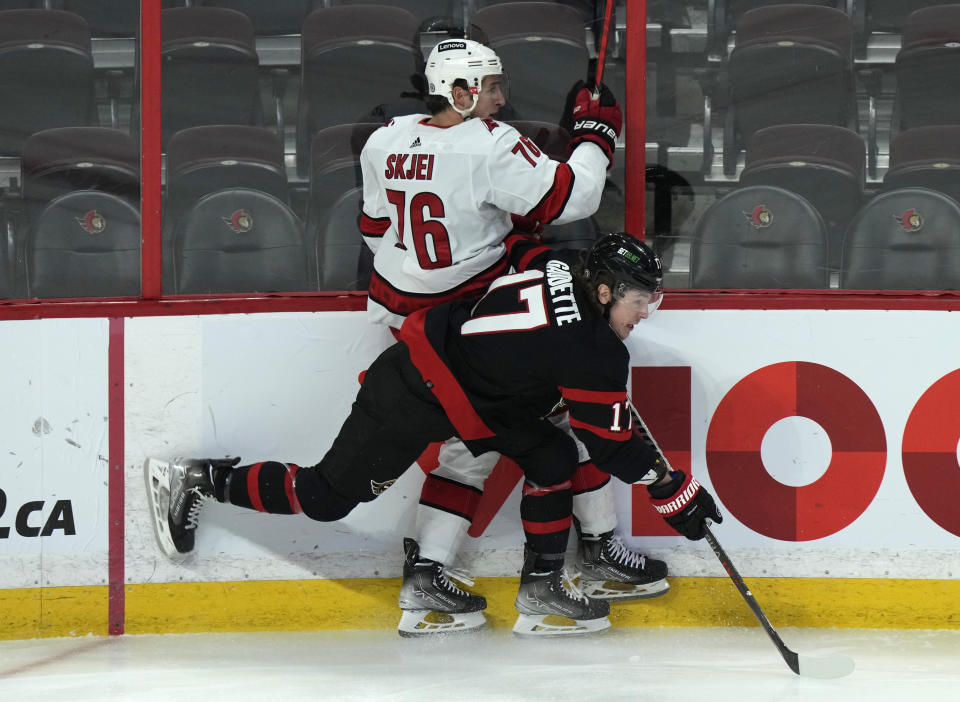 Ottawa Senators center Adam Gaudette collides with Carolina Hurricanes defenseman Brady Skjei along the boards during the first period of an NHL hockey game, Thursday, Jan. 27, 2022 in Ottawa, Ontario. (Adrian Wyld/The Canadian Press via AP)