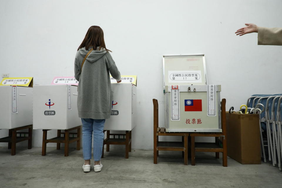 A voter casts her vote into a ballot box at a polling station during a four-question referendum in Taipei, Taiwan December 18, 2021. REUTERS/Annabelle Chih