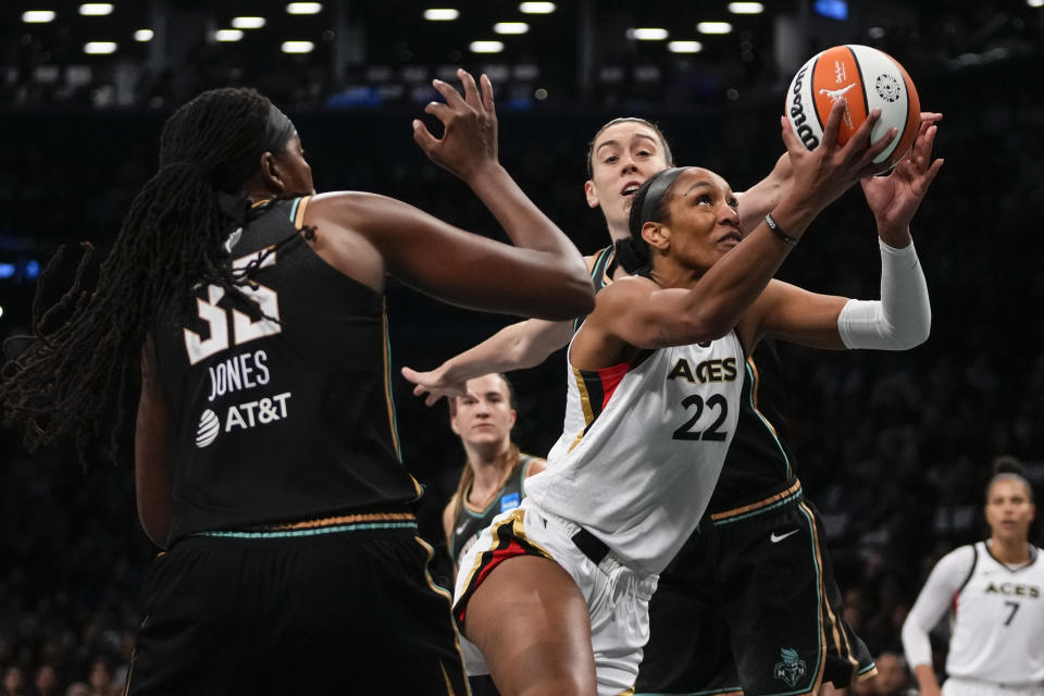 Las Vegas Aces' A'ja Wilson (22) drives past New York Liberty's Breanna Stewart and Jonquel Jones during the first half in Game 3 of a WNBA basketball final playoff series, Sunday, Oct. 15, 2023, in New York. (AP Photo/Frank Franklin II)