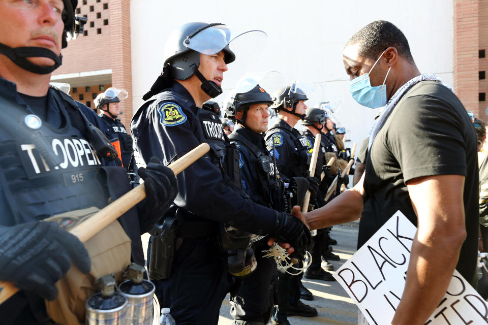 A demonstrator shakes hands with a police officer during a protest on May 31, 2020 in Kansas City, Missouri. (Photo by Jamie Squire/Getty Images)