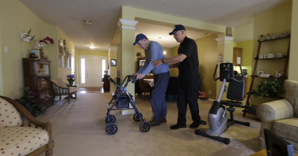 In this Nov. 27, 2013 photo, caregiver Warren Manchess, right, walks across the living room with Paul Gregoline, 92, in Noblesville, Ind. Three days a week, Manchess, 74, arrives at Gregoline's house, giving the retired electrician's wife a needed break. Burgeoning demand for senior services like home health aides is being met by a surprising segment of the workforce: Other seniors. Twenty-nine percent of so-called direct-care workers are projected to be 55 or older by 2018 and in some segments of that population older workers are the single largest age demographic. With high rates of turnover, home care agencies have shown a willingness to hire older people new to the field who have found a tough job market as they try to supplement their retirement income.(AP Photo/Darron Cummings)